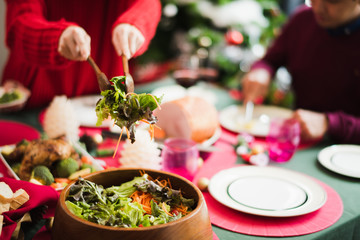 Young Asian family celebration in Christmas day, mother take meal salad to father which smiling and felling happy love in kitchen at home in morning time. Merry Xmas.