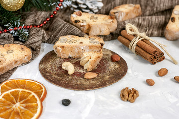 Fototapeta na wymiar Traditional Italian biscotti or Cantuccini cookies with hazelnuts, almonds, walnuts on a gray background with slices of dried oranges and cinnamon.