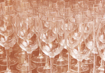 Close up rows of empty wine glasses on colored background in color 2020. Brown color trend by 2020