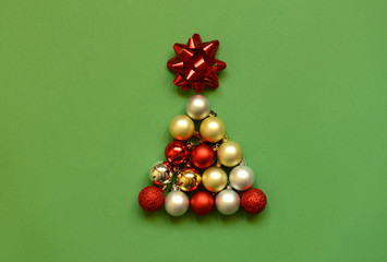 Christmas tree shape made with bauble on green background. Minimal holiday concept. Creative flat lay.