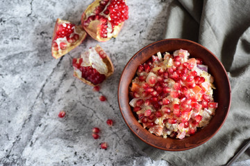 Meat salad with pomegranate seeds and vegetables in a clay bowl on a gray background