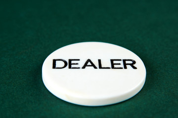 Casino dealer chip on green background with copy space.