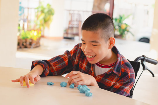 Asian disabled child on wheelchair molding clay, Fun and entertaining activity for training small and large muscles, Lifestyle in the education age of special need kids, Happy disability kid concept.