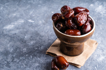 Tasty palm dates in bawl on gray stone table Copy space.