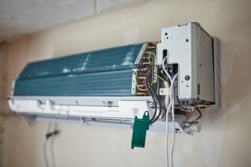 Split air conditioner closeup repair and maintenance concept. The specialist repairs the wall air...