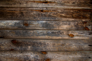 Old pine horizontal boards. The wood texture is brown-gray with rings from knots and scuffs....