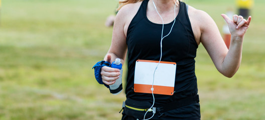 Women running race puts her thumpb and pinky up to photographer