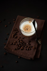 Top view on thermo glass cup of latte coffee on dark wooden table. Morning beverage