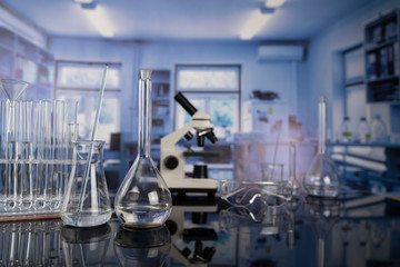 Science laboratory. Beakers, test-tubes and microscope on glass table in the laboratory.