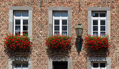 Fototapeta na wymiar detail of brick house with beautiful red flower boxes outside in Aachen, Germany