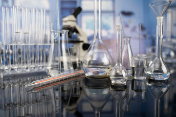 Science laboratory. Beakers, test-tubes and microscope on glass table in the laboratory.