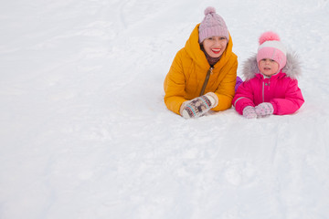 Fototapeta na wymiar happy family mother and baby girl daughter playing and laughing in winter outdoors in the snow