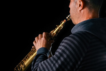 soprano saxophone in the hands of a guy on a black background