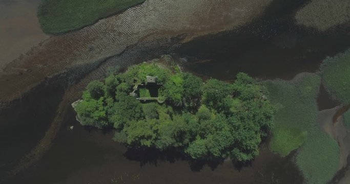High rising top-down aerial over the ancient ruins of Loch Dochart Castle on an island surrounded by rippling water in the middle of the loch in the Scottish Highlands