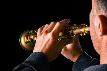 soprano saxophone in the hands of a guy on a black background
