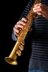 soprano saxophone in the hands of a guy on a black background
