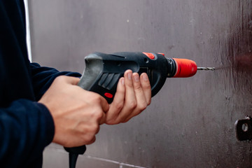 Hands of a man drills with an electric drill