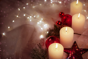 4 weiße Kerzen mit roter Weihnachtsdekoration in verträumter Athmosphäre
