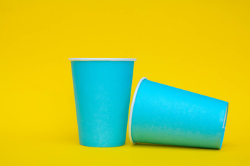 Two blue paper cups on yellow background. Copy, empty space for text