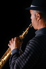 soprano saxophone in the hands of a guy on a black background