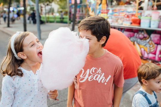 Cheerful kids enjoying sweet candyfloss on street
