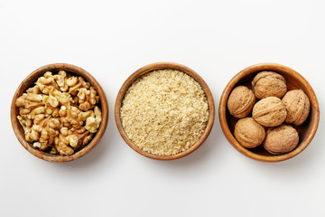 Whole walnuts, walnut kernel and ground walnuts in wooden bowls .