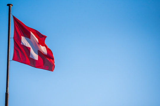 swiss flag waving in the wind against blue sky