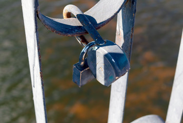 Old padlock on the railing of the bridge closeup. Symbolic love padlocks fixed to the railings bridge as a eternal love sign.