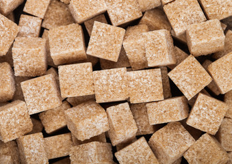 Close-Up shot of natural brown sugar cubes on white background.