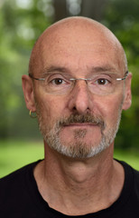 Face of retired man about 60 years old in green forest backyard