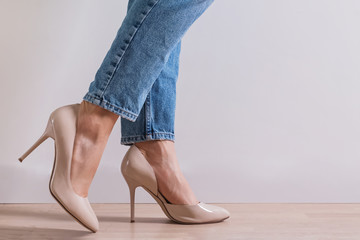 Woman's feet close-up wearing high heel shoes and jeans - obrazy, fototapety, plakaty