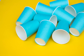 Many blue paper disposable cups on yellow background. Set for party. Top view. Minimalist Style. Copy, empty space for text