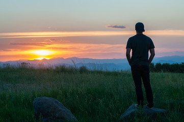 A young person enjoying a sunset over a mountain range