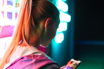 Image of beautiful woman holding smartphone over neon text sign