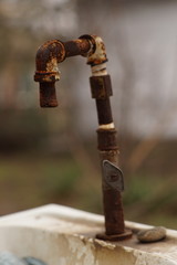 Old rusty self-made the water faucet on the sink in the rural co