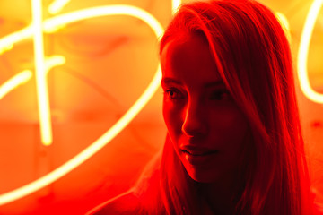 Image of young caucasian woman standing over red neon text sign outdoors