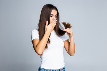 Sad girl looking at her damaged hair isolated on white background