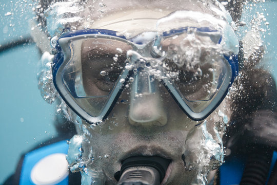 primer plano de la cara de un buceador dentro del mar haciendo burbujas mientras respira. buceo recreativo. snorkel.