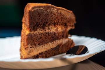 A piece of sponge chocolate cake on a white plate on a black background.