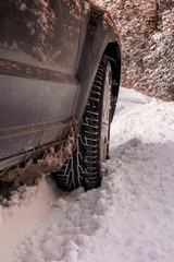 Car tires on winter road covered with snow. Vehicle on snowy alley in the morning at snowfall