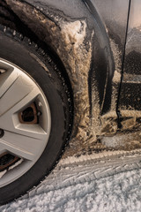 Adhered to the body of the car dirty snow from the road. photo close-up of car details. rusty car, metal corrosion and traces of reagents, winter Moscow city.