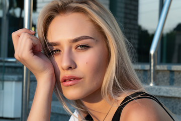 Close up portrait of a pretty blonde girl with natural heakthy skin that looking at the camera, sun's rays fall on her face