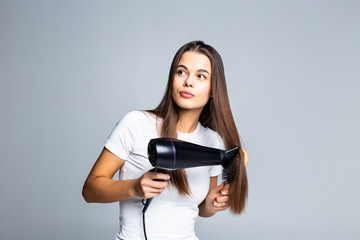 Portrait of beautiful woman holding hair dryer isolated on gray background