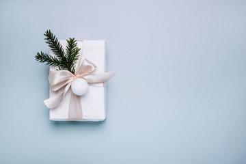 Fototapeta na wymiar Gift, fir tree branches, white ribbon and ball light on blue background. Christmas, winter, new year concept. Flat lay, top view, copy space