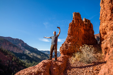 Excited hiker taking a selfie with an arm extended to show off the view.