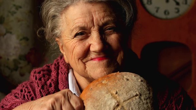 Elderly woman eating a big bun and smile