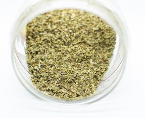Fresh oregano inside a glass bowl on white background.