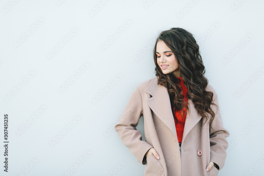 Wall mural Hipster girl wearing orange t-shirt, jeans and coat posing against rough street wall, minimalist urban clothing style, mockup for tshirt print store