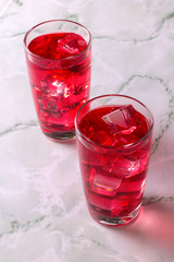 Glass of mango dragonfruit refresher drink on marble table with ice cubes. Copy space.