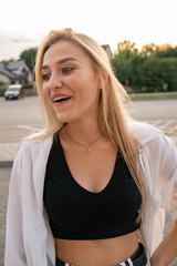 Waist up portrait of a surprised blonde girl in black top, looking at lower left corner
